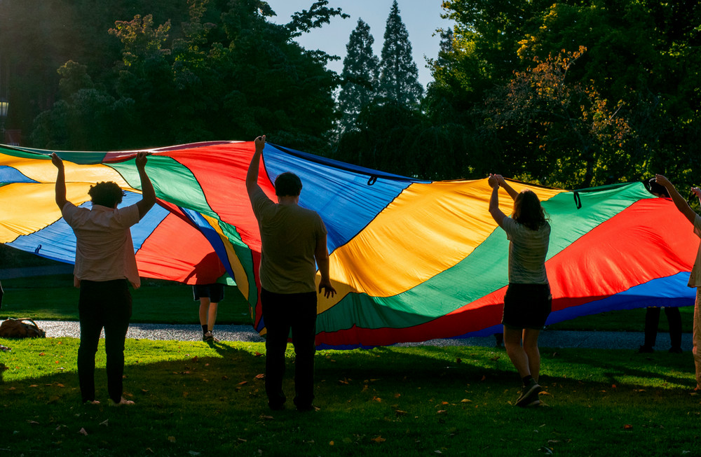 photo of a large colorful tarp being thrown up in the air